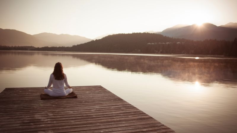 Ein Foto von einer Frau, die an einem See meditiert