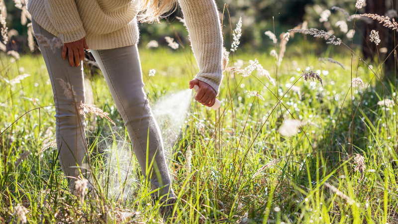 Eine Person, die sich mit Insektenschutzmittel gegen Zecken schützt.